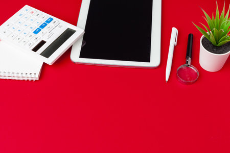 Red office desk table with blank notebook, keyboard and supplies. Top view with copy space. Flat lay.の写真素材