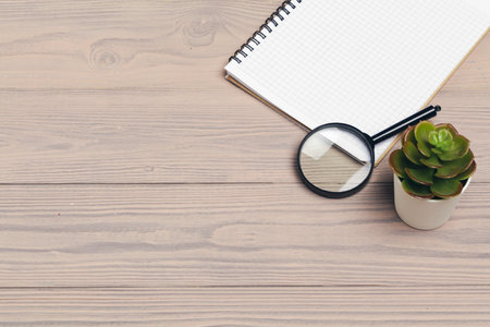 Magnifying glass and notebook on wooden tableの写真素材