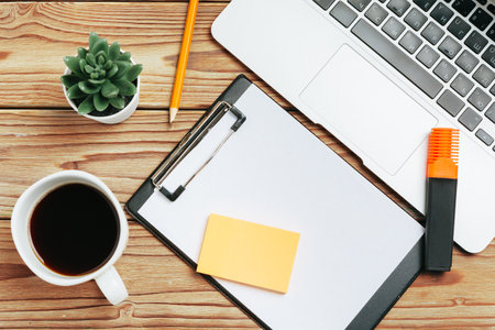 Wooden office desk table and equipment for working with black coffee in angle viewの写真素材