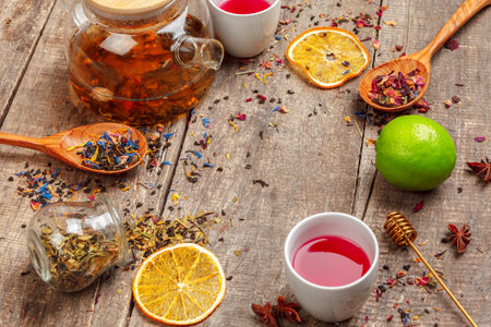 cups of healthy herbal tea with cinnamon, dried rose and camomile flowers in spoons over wooden background, top viewの写真素材