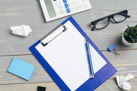 Clipboard with blank paper for copy space and supplies on wooden table