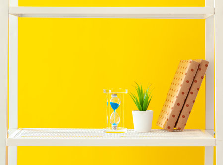 White shelf with stationery objects against bright yellow background