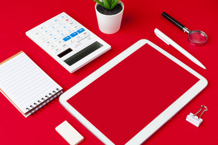Red office desk table with blank notebook, keyboard and supplies. Top view with copy space. Flat lay.の写真素材