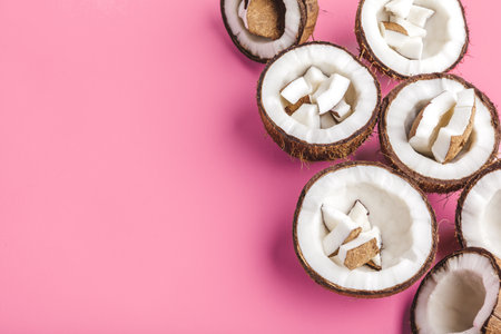 Broken coconut pieces on bright pink background, top view, copy spaceの写真素材