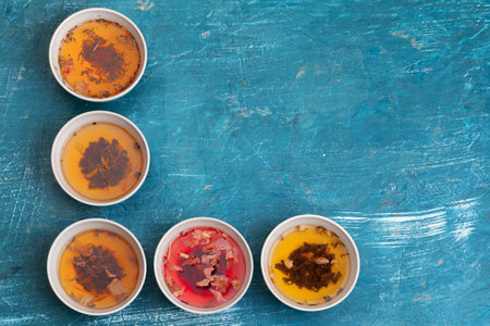 Tea concept. Different kinds of dry tea in ceramic bowls and cups of aromatic teaの写真素材