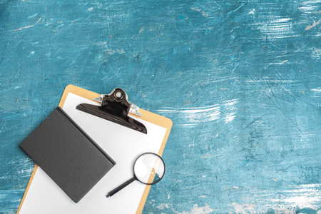 Magnifying glass and notebook on wooden table