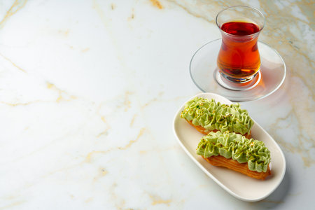 Eclair cake with pistachio glaze on white plate