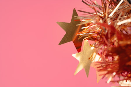 Colorful tinsel Christmas decorations close-up on pink backgorund