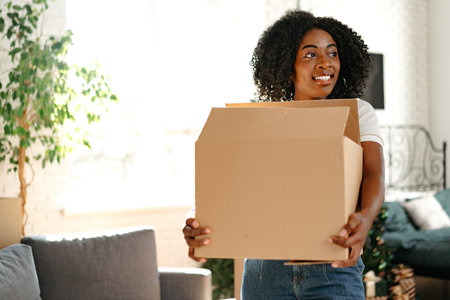 Happy african young woman with cardboard box moving to a new place