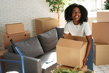 Happy african young woman with cardboard box moving to a new place