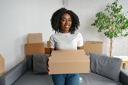 Happy african young woman with many cardboard boxes at home