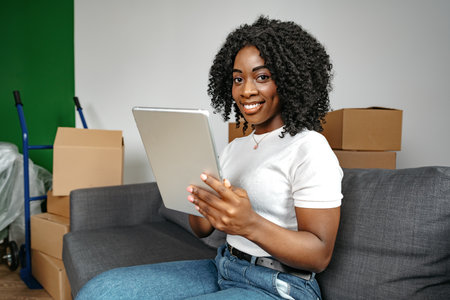 Young african woman using digital tablet and smiling while resting at home.