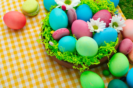 Easter composition with colored eggs and bright candies on yellow tablecloth