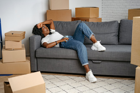 Happy african young woman with many cardboard boxes at home