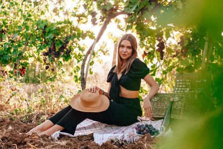 Young blonde woman sitting on a picnic in a vineyard