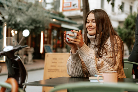 Stylish young woman drinking coffee at the coffee shopの写真素材