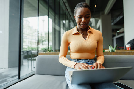 African female student working on computer in public place