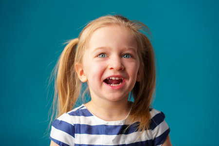 Funny little toddler girl smiling against blue background