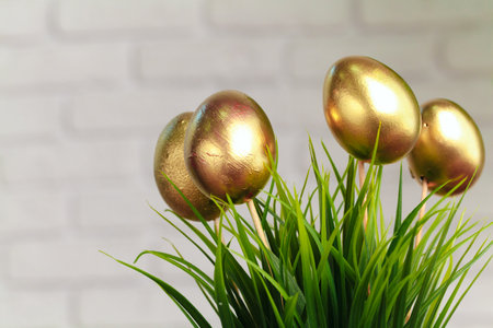 Golden colored Easter eggs stuck to artificial grass