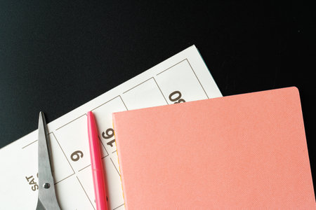 Notepad with pen and scissors on black table close upの写真素材