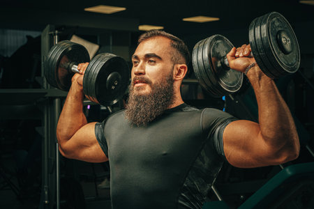 Muscular young man lifting weights in a dark gym
