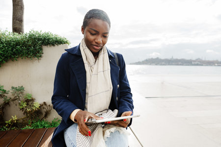 Black happy woman using a digital tablet outdoors