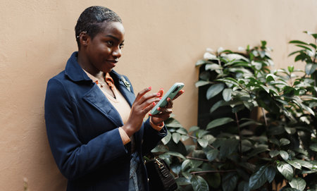 Young african woman smiling and using smartphone at the city
