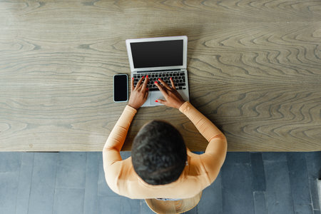 Young african woman freelancer working on laptop while sitting in coworkingの写真素材