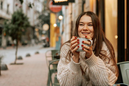Stylish young woman drinking coffee at the coffee shopの写真素材
