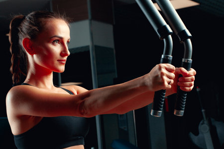 Young attractive woman doing exercises for arms in a training machineの写真素材