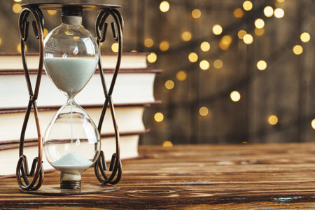 Hourglass on wooden desk against blurred lightsの写真素材