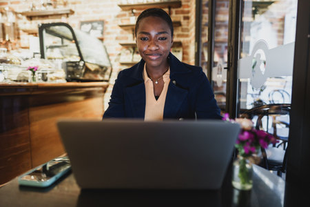 African woman having a video call on laptop while sitting in cafe.の写真素材