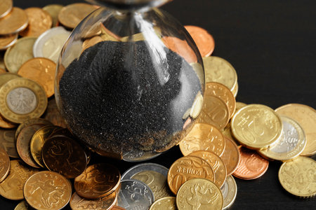 Time is money. Close up of hourglass with money coins