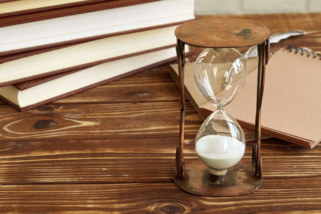 Vintage hourglass against a stack of old books