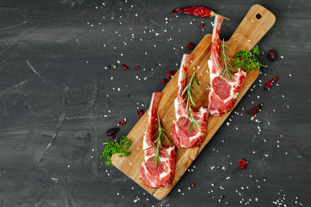 Racks of lamb ready for cooking on dark background