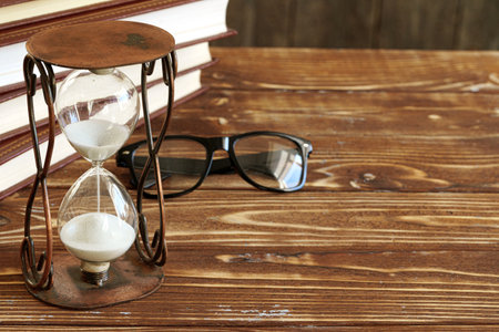 Vintage hourglass against a stack of old books