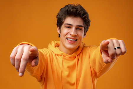 Positive smiling young male choosing you over yellow backgroundの写真素材