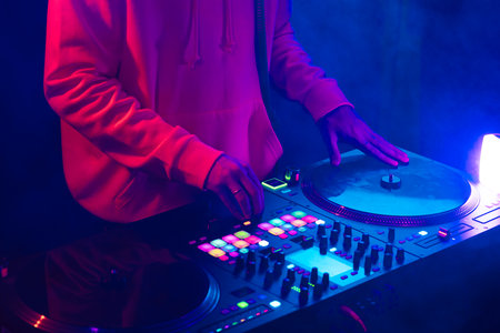 Hands of a DJ creating and regulating music on dj console mixer at club concertの写真素材