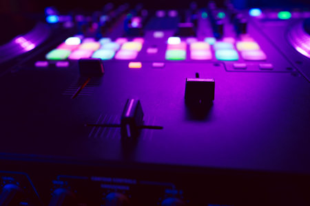 Close up of DJ mixing console in party lightの写真素材