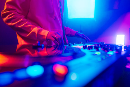 Hands of a DJ creating and regulating music on dj console mixer at club concertの写真素材