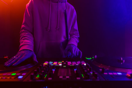 Hands of a DJ creating and regulating music on dj console mixer at club concertの写真素材
