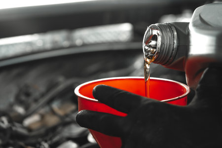 Close up of car service worker pouring new oil into car engineの写真素材