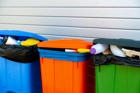 Three trash containers full of garbage near the buildingの写真素材