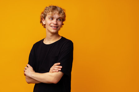 Young smiling happy caucasian man with blonde curly hair against yellow backgroundの写真素材