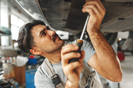 Workman mechanic working under car in auto repair shopの写真素材