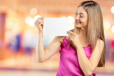 Happy smiling beautiful young woman in pink smart casual clothing showing blank signboard or copyspace for slogan or textの写真素材