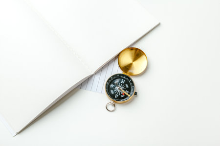 Golden compass with black notepad and pen close up on a tableの写真素材