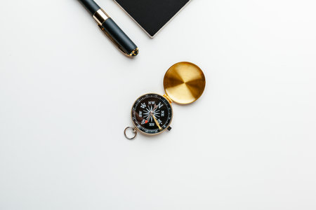 Black notepad for nautical notes and golden compass on a white tableの写真素材