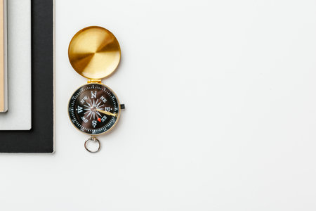 Black notepad for nautical notes and golden compass on a white tableの写真素材