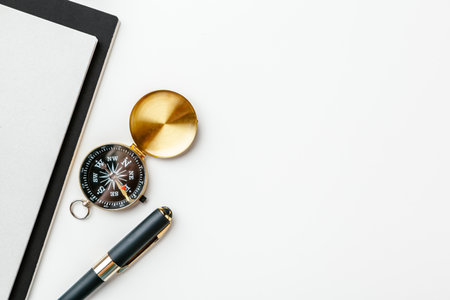 Black notepad for nautical notes and golden compass on a white tableの写真素材